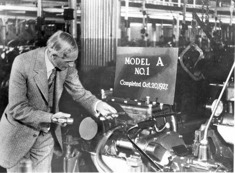 Henry Ford punches the engine number on the first Ford Model A off the assembly line.